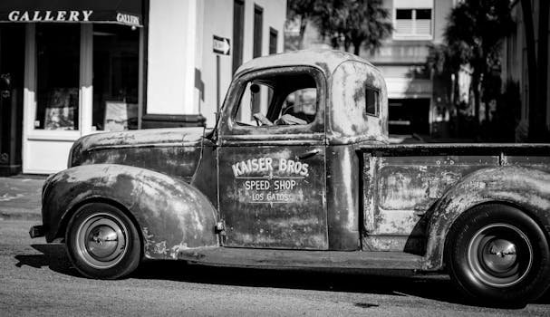 Black and white photograph of a vintage pickup truck parked on a city street.